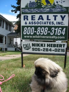 Riley posing (sort of) next to real estate sign.